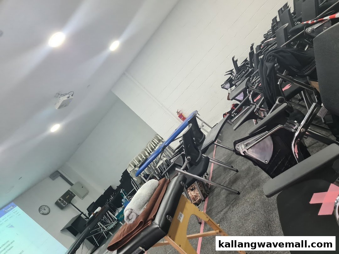 Interior view of a training room with stacked chairs, massage tables, and a projector screen.