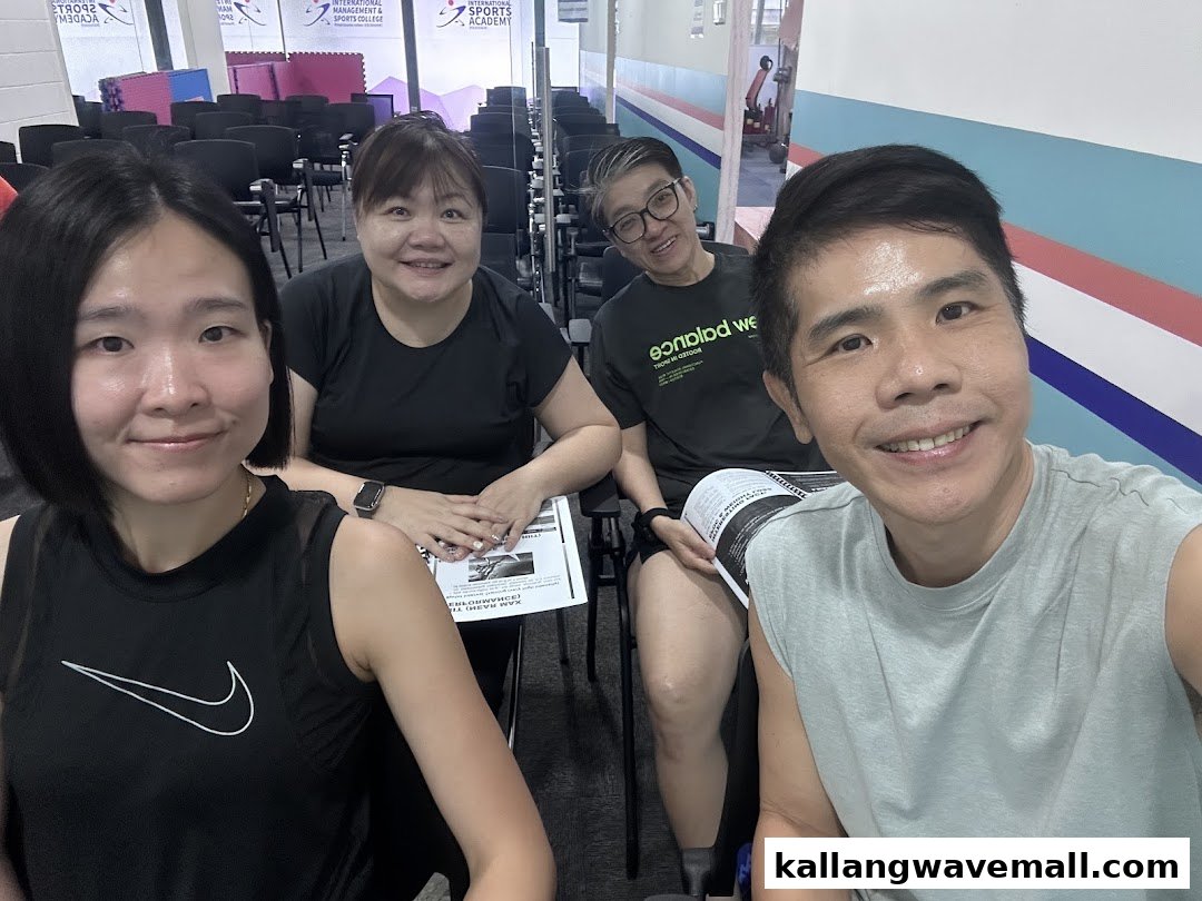 Four smiling individuals in a classroom setting at the International Sports Academy.