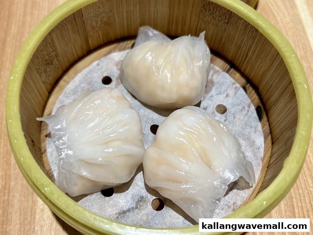 Three translucent steamed shrimp dumplings (har gow) served in a traditional bamboo steamer.
