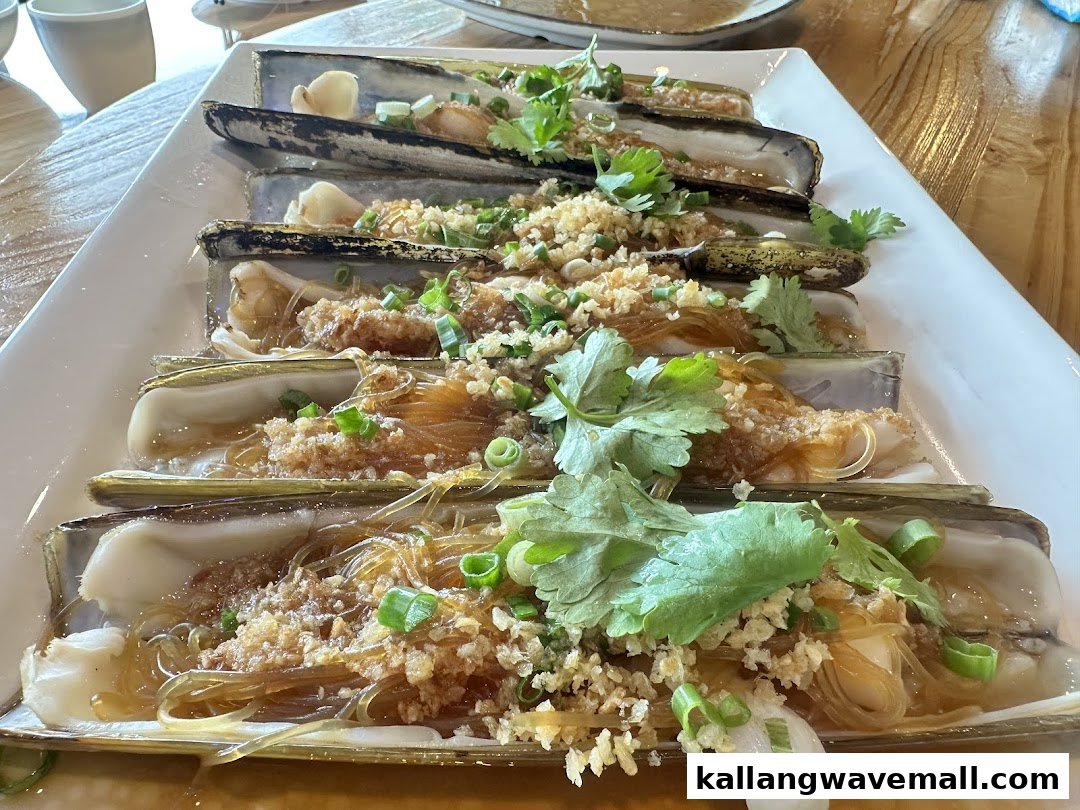 A platter of steamed razor clams with vermicelli, minced garlic, and fresh herbs.