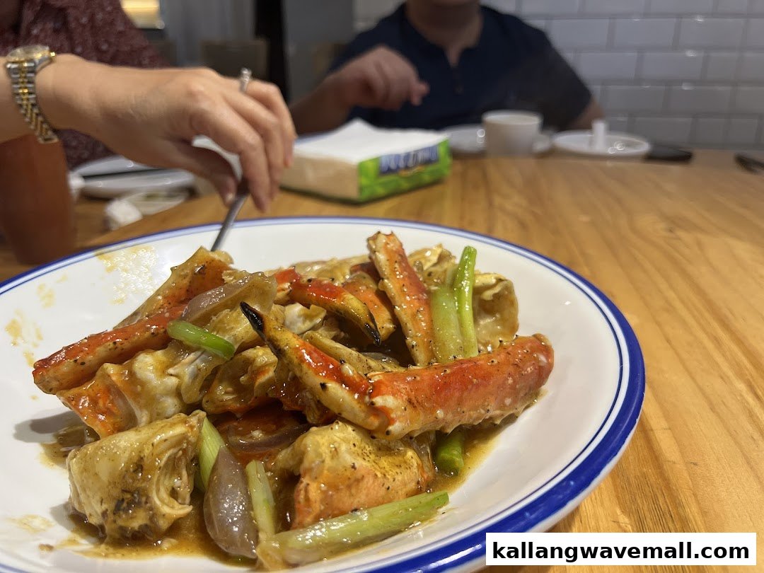 A close-up of a delicious plate of cooked crab with sauce and vegetables on a wooden table.