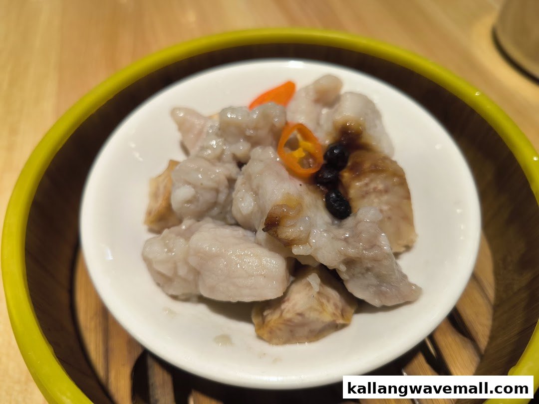 Steamed pork ribs with taro and black bean sauce in a white dish inside a bamboo steamer.