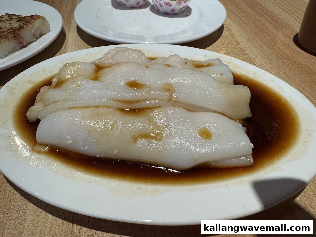 A close-up of steamed rice noodle rolls (Cheung Fun) with soy sauce, served on a white plate.