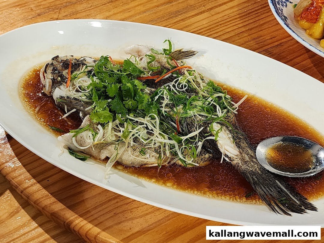 A beautifully presented steamed whole fish, garnished with fresh scallions and cilantro, in a savory sauce.