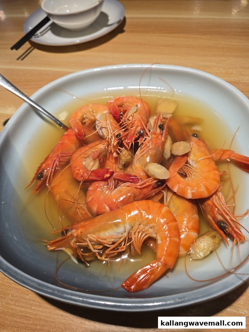A vibrant plate of steamed prawns in a flavorful broth, garnished with ginger slices.