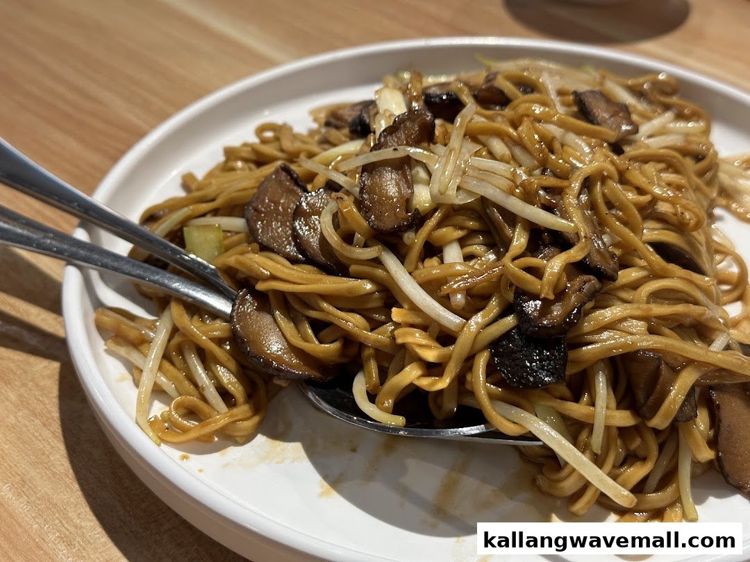 A close-up of stir-fried noodles with mushrooms and bean sprouts on a white plate.