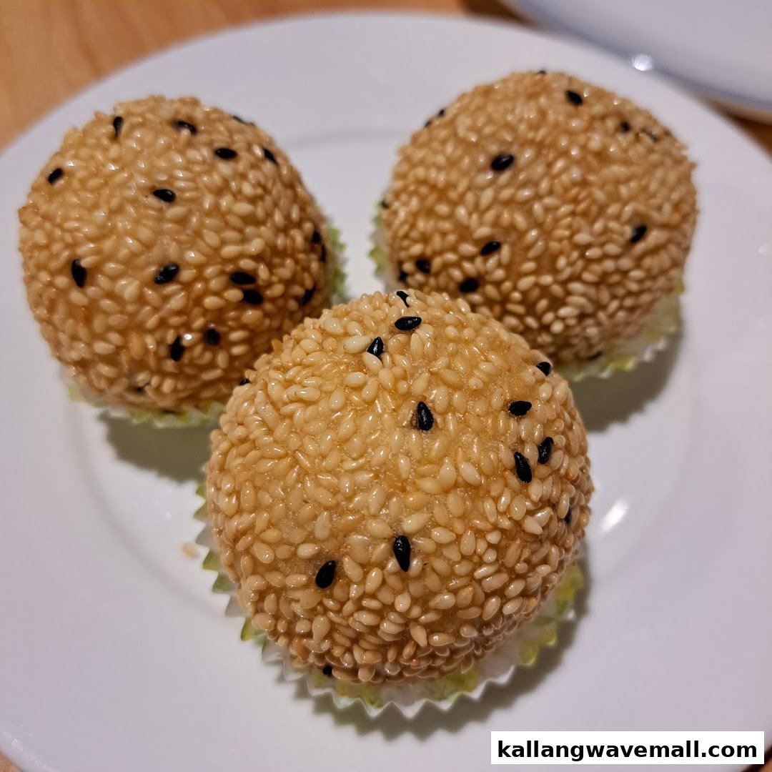Three golden-brown sesame balls, also known as Jian Dui, are served on a white plate.
