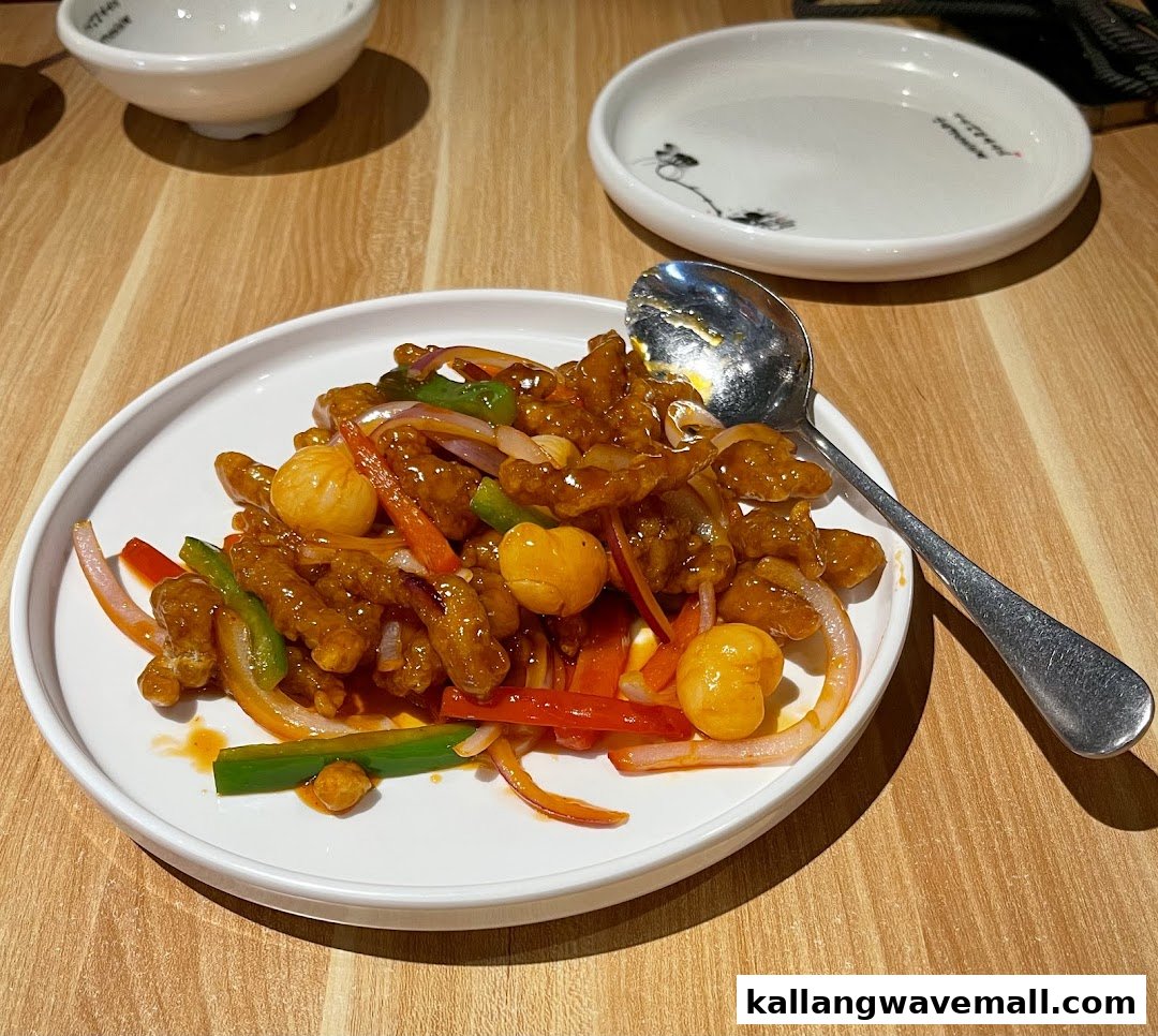 A vibrant plate of sweet and sour pork with bell peppers and onions on a wooden table.