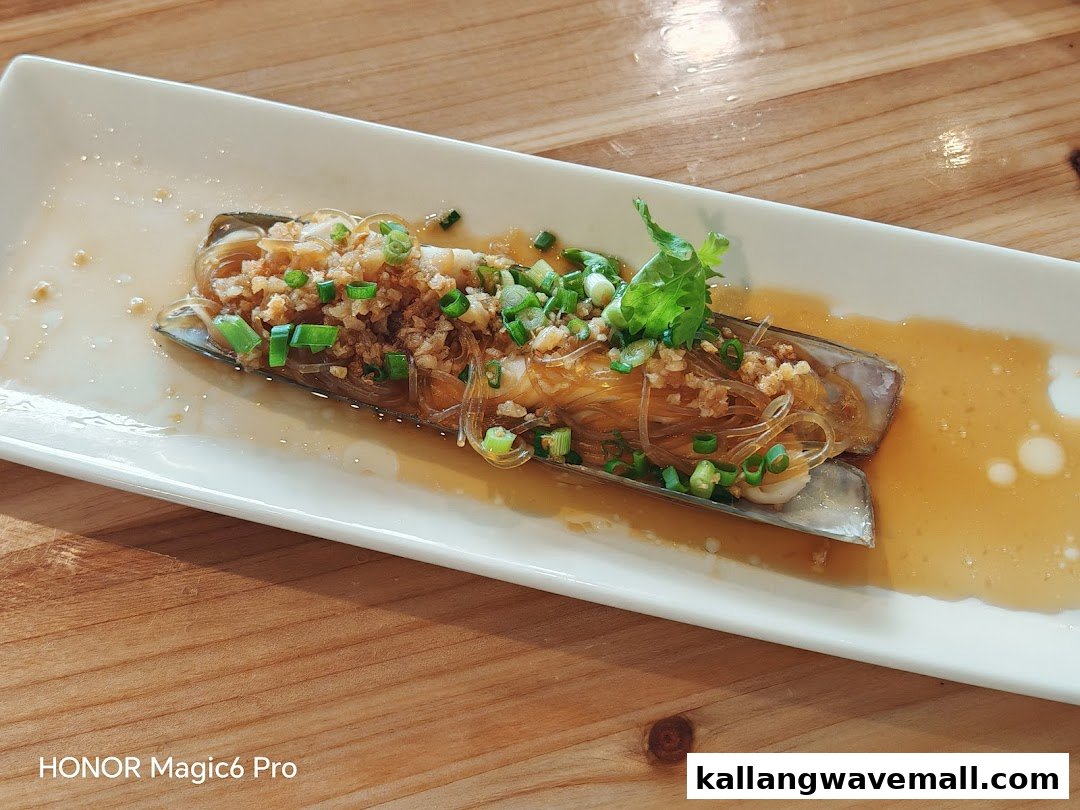 A delicious dish of steamed razor clams with vermicelli, garlic, and scallions on a white plate.