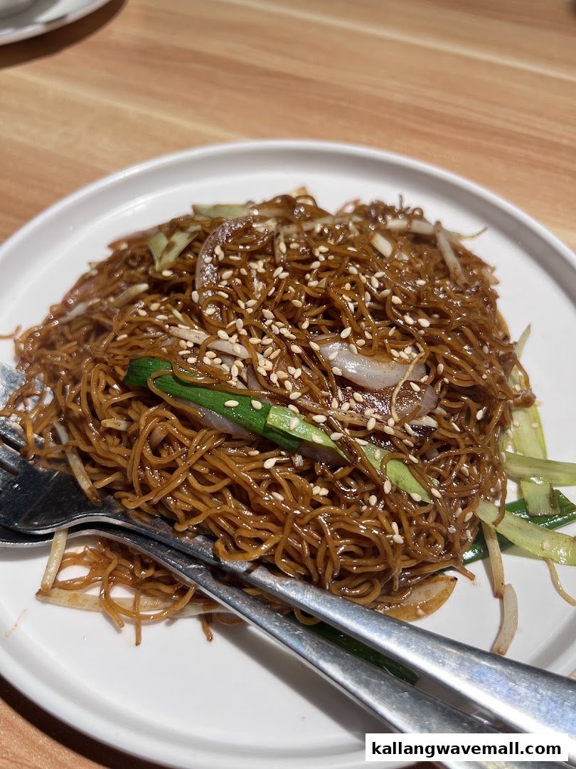 A close-up of a delicious plate of stir-fried noodles with vegetables and sesame seeds.