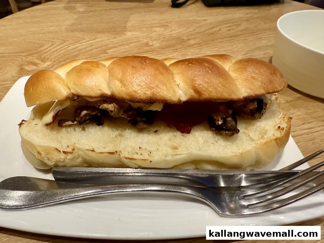 A close-up of a savory sandwich filled with mushrooms and cheese on a braided bun.