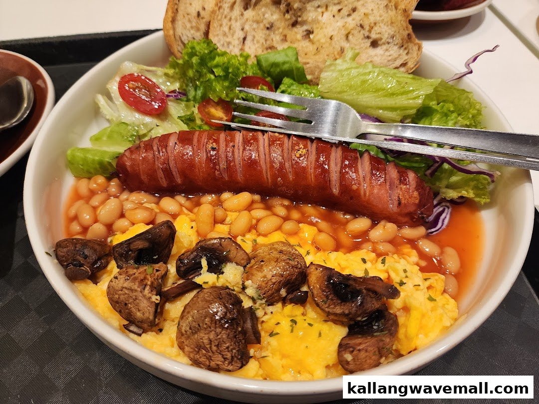 A hearty breakfast plate featuring sausage, scrambled eggs, baked beans, mushrooms, and a fresh salad.