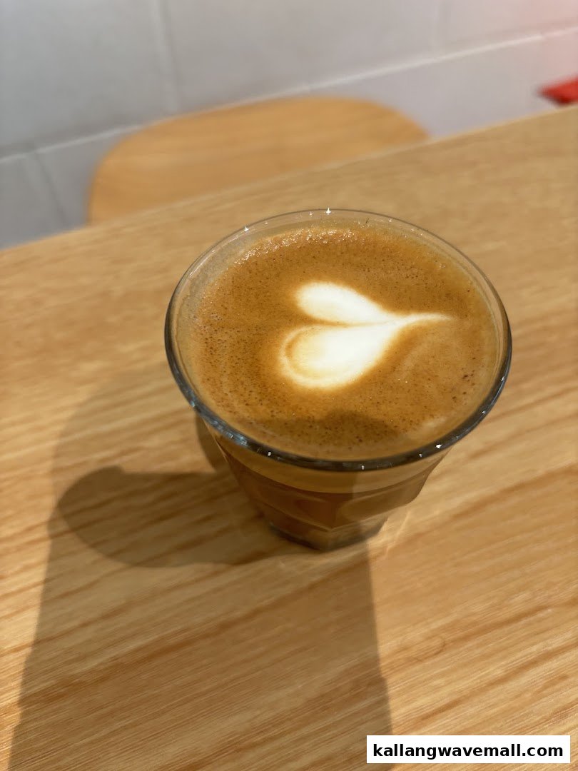 A close-up of a coffee cup with heart-shaped latte art on a wooden table.