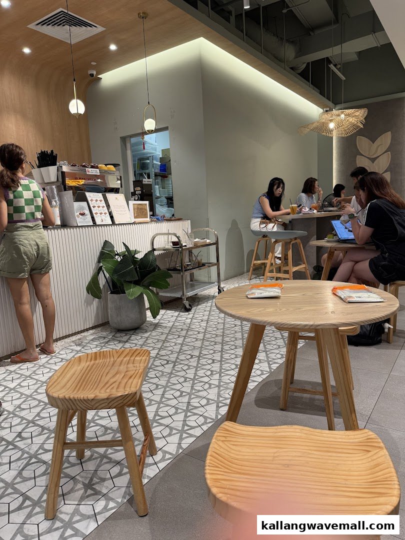 A modern cafe interior with customers enjoying drinks and a counter area, featuring light wood and patterned tiles.
