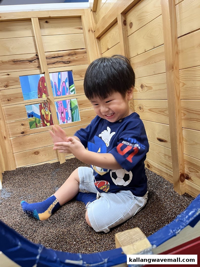A joyful child plays happily in a wooden play structure with a textured floor.