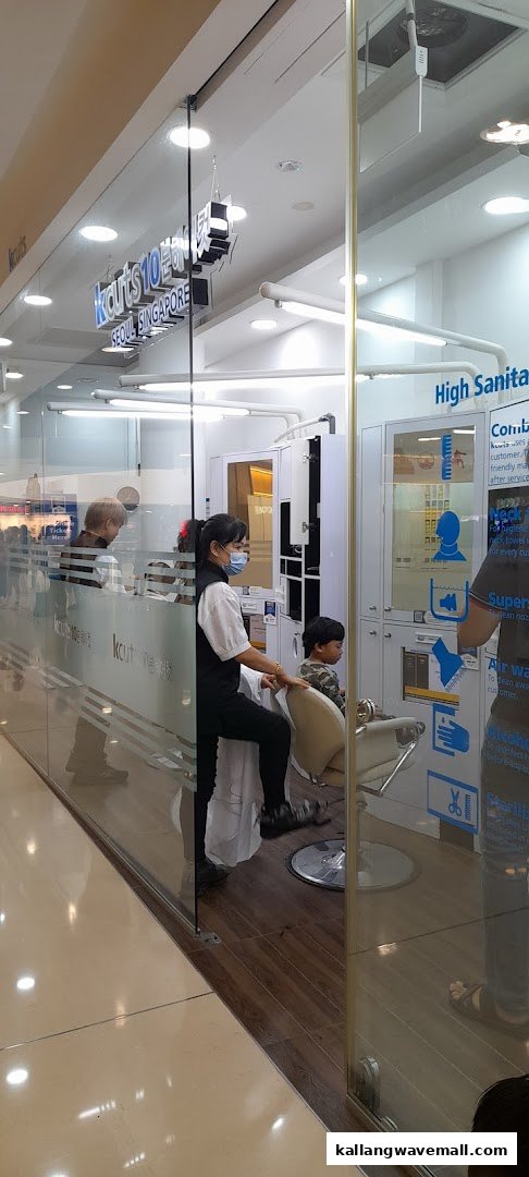 A stylist attends to a child inside the glass-fronted kcuts hair salon at Kallang Wave Mall.