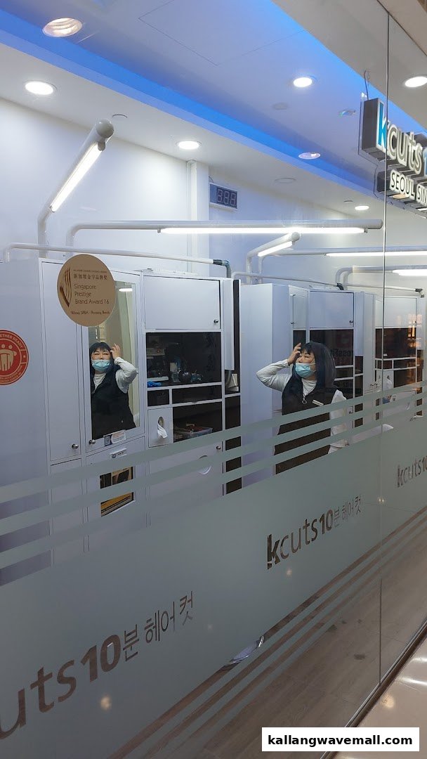 View into kcuts hair salon, showing stylists and compact cutting stations through a frosted glass facade.