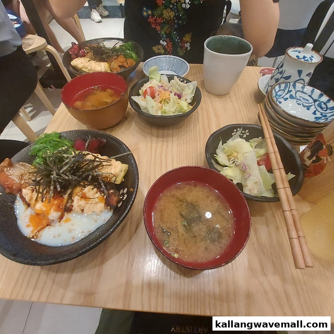 Two delicious Japanese donburi bowls with miso soup and salads on a wooden table.