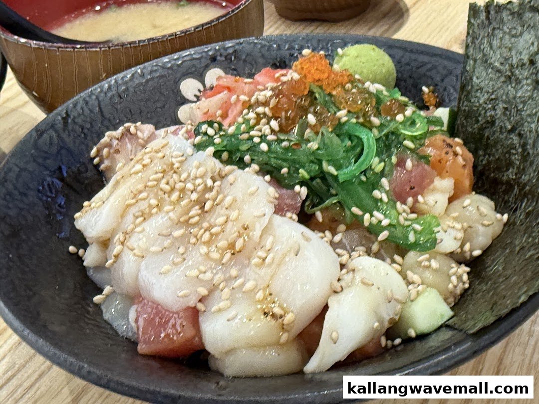 A vibrant kaisendon bowl featuring fresh seafood, seaweed, roe, and sesame seeds, served with miso soup.