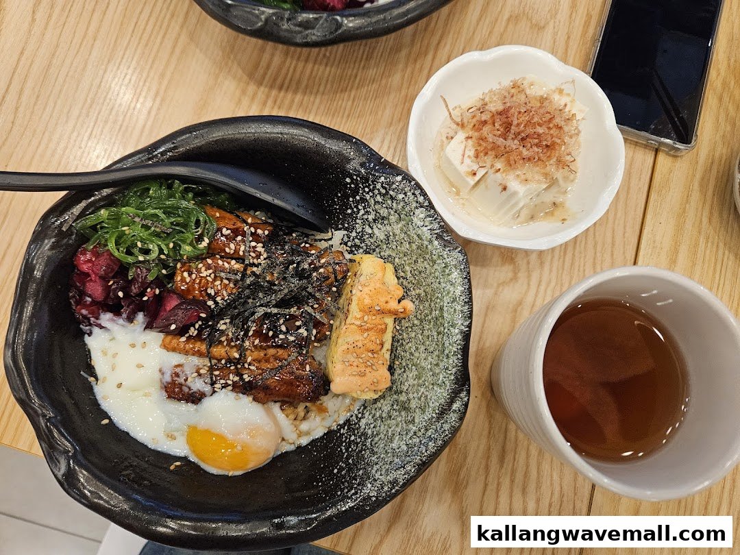 A Japanese unagi donburi with egg, seaweed, and pickled vegetables, served with tofu and tea.