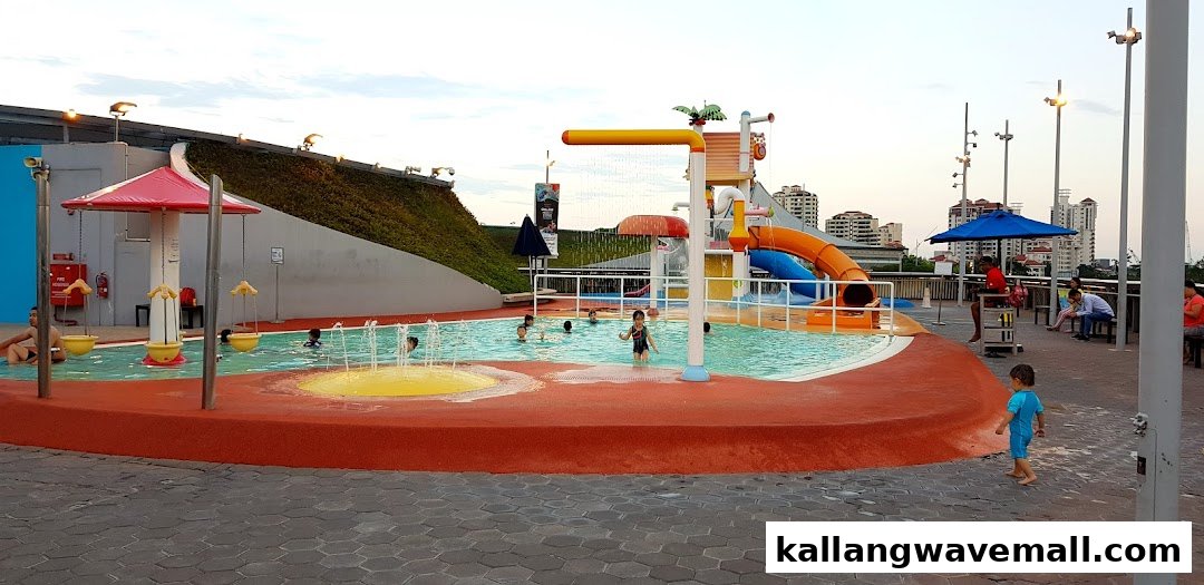 Children and adults enjoying a vibrant outdoor water play area with slides and fountains.