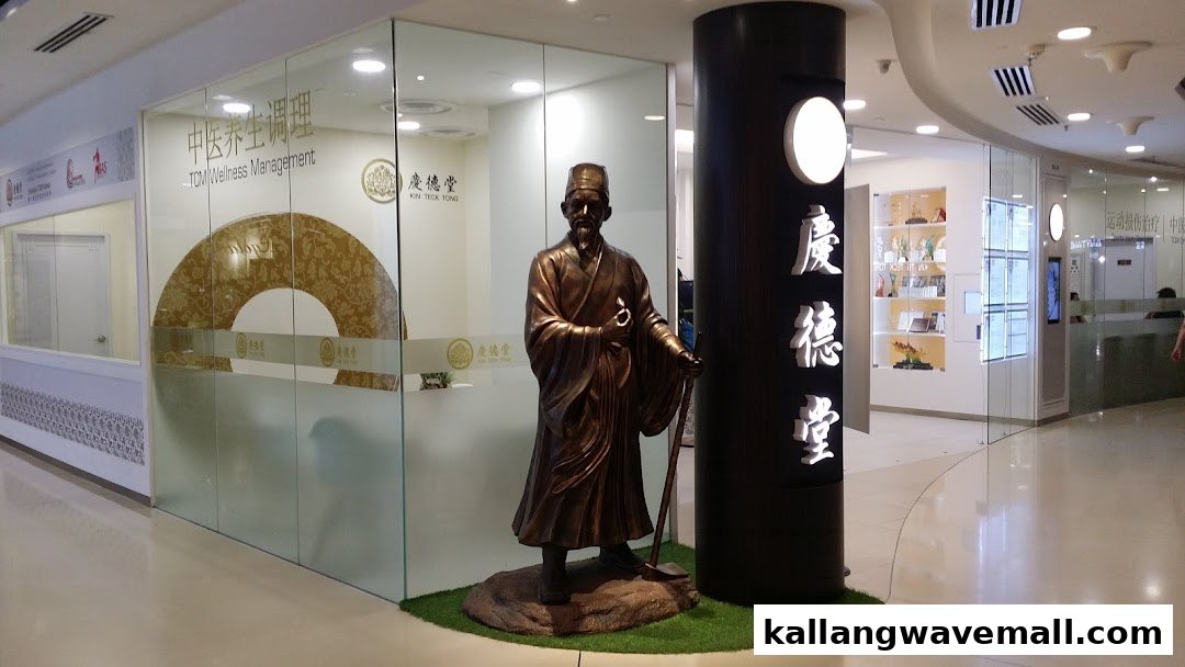 The entrance of Kin Teck Tong TCM Clinic, featuring a traditional statue and glass facade.