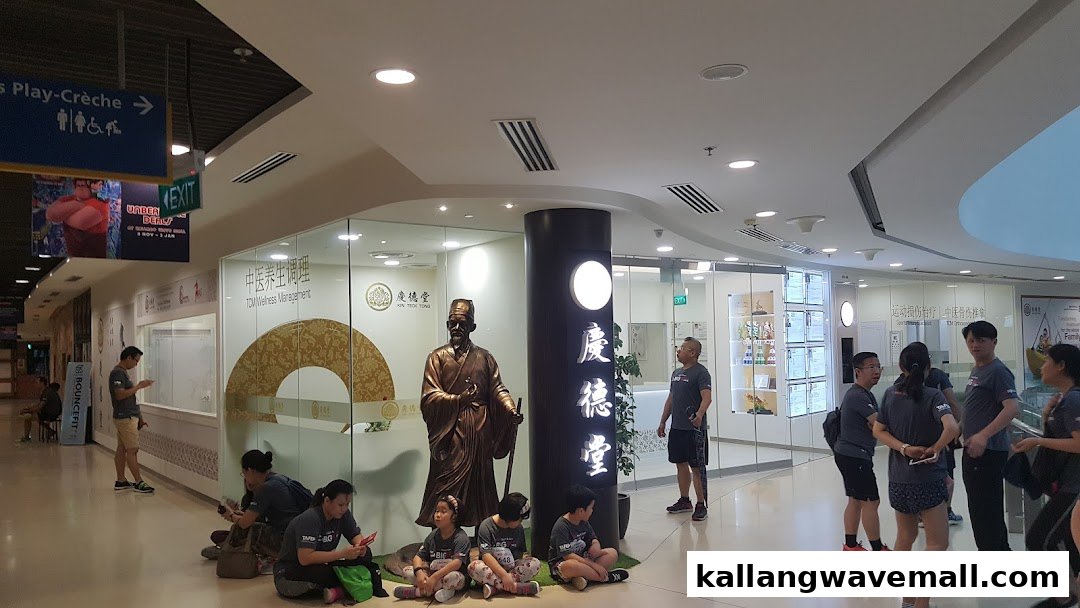 The entrance of Kin Teck Tong TCM Clinic, featuring a traditional statue and glass facade within a mall.