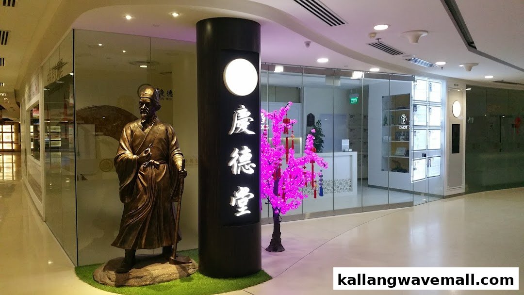 The entrance of Kin Teck Tong TCM Clinic, featuring a traditional statue and a vibrant pink cherry blossom tree.