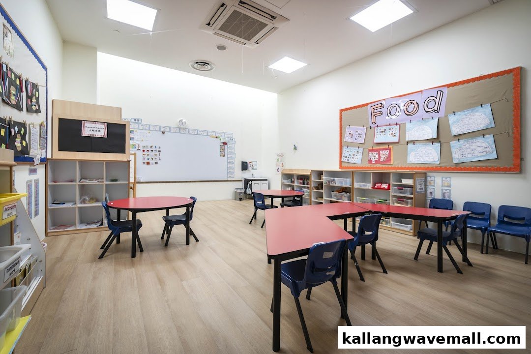 A bright, spacious preschool classroom with red tables, blue chairs, whiteboards, and learning displays.