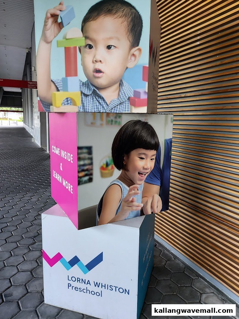 An outdoor standee for Lorna Whiston Preschool featuring images of happy, playing children.