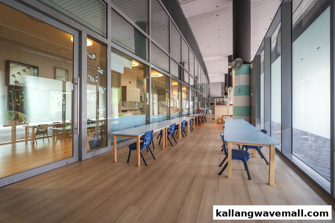 Bright, spacious hallway of a preschool with classrooms visible through glass walls and children's tables.