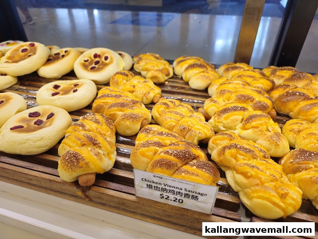 A vibrant display of freshly baked breads and pastries, including sweet buns and savory sausage rolls.
