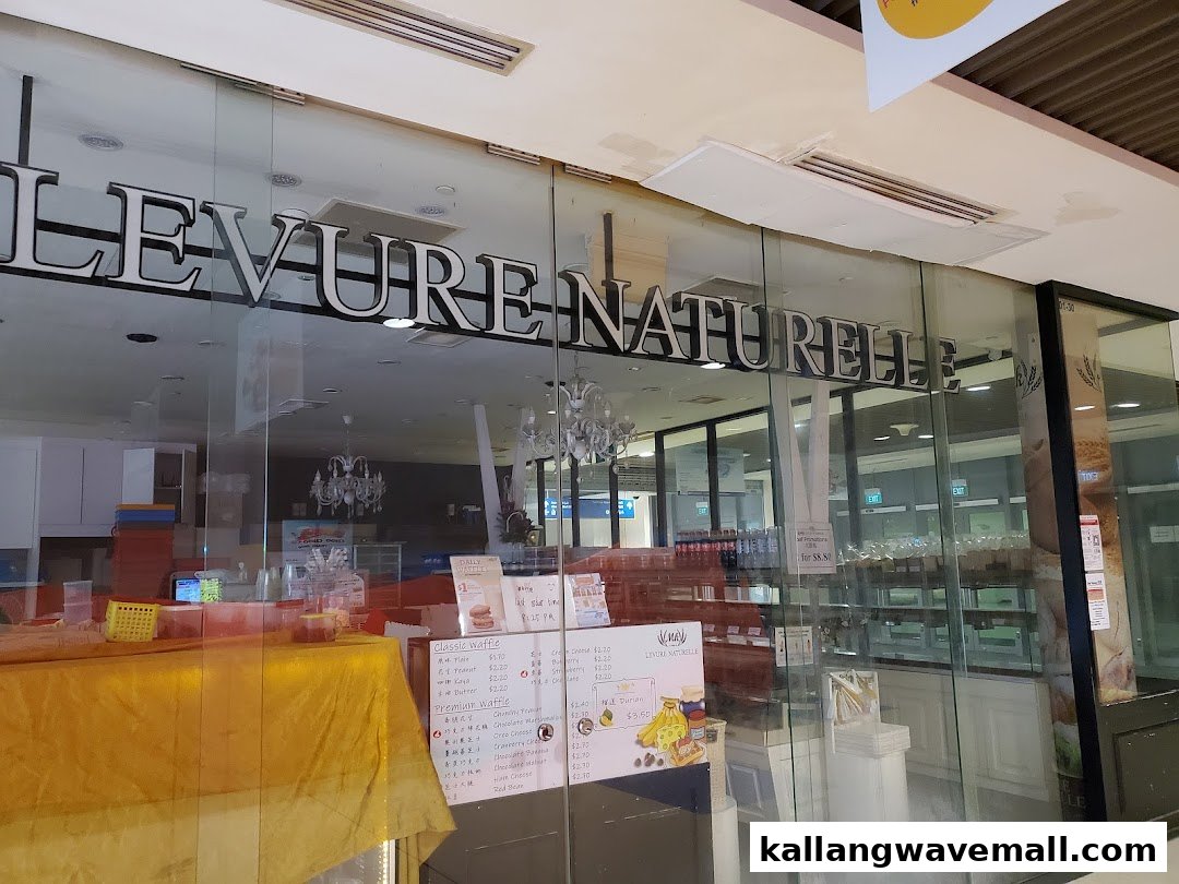The glass storefront of Levure Naturelle, a bakery or waffle shop, showcasing interior displays and menu signs.