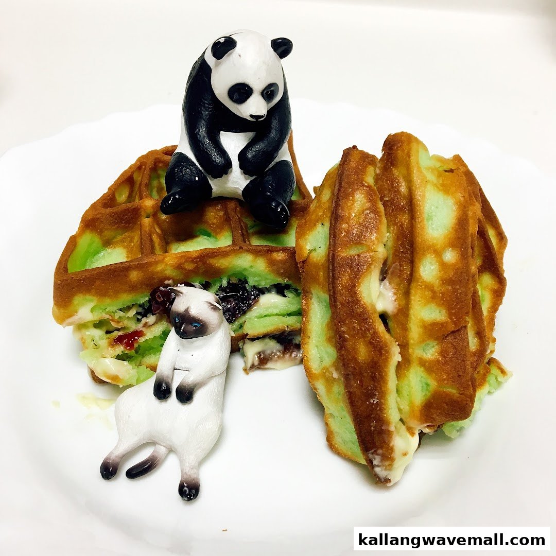 A plate of green-tinted waffles with fillings, adorned with small panda and cat figurines.