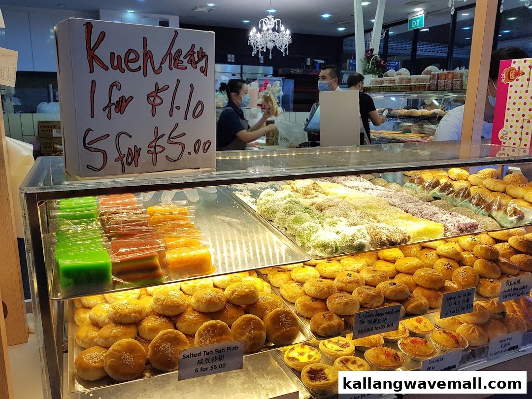 A vibrant display case filled with a variety of traditional Asian pastries, kueh, and baked goods at MK Levure Naturelle.