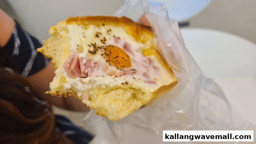 A close-up of a savory baked good with a whole egg, ham, and cheese, sprinkled with pepper.