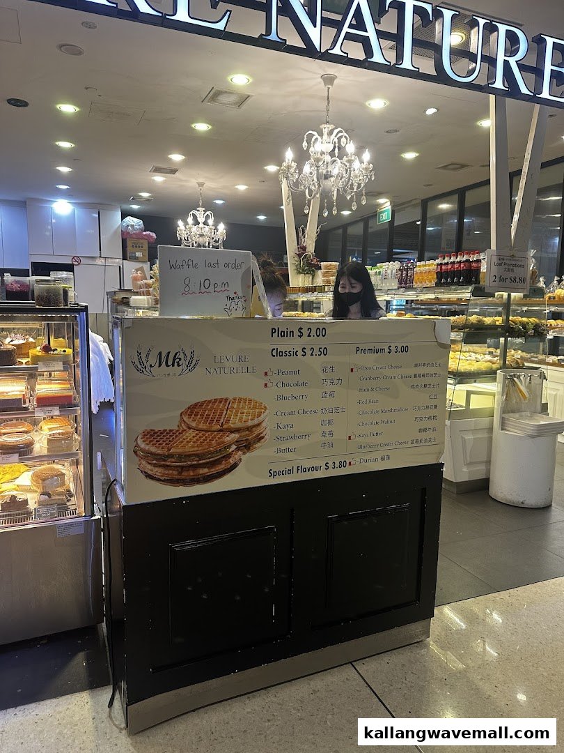 A counter at MK Levure Naturelle displaying a waffle menu, with staff and baked goods visible.