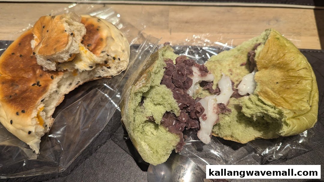Close-up of two unique sweet buns, one with yellow filling and sesame, the other green with red bean and mochi.