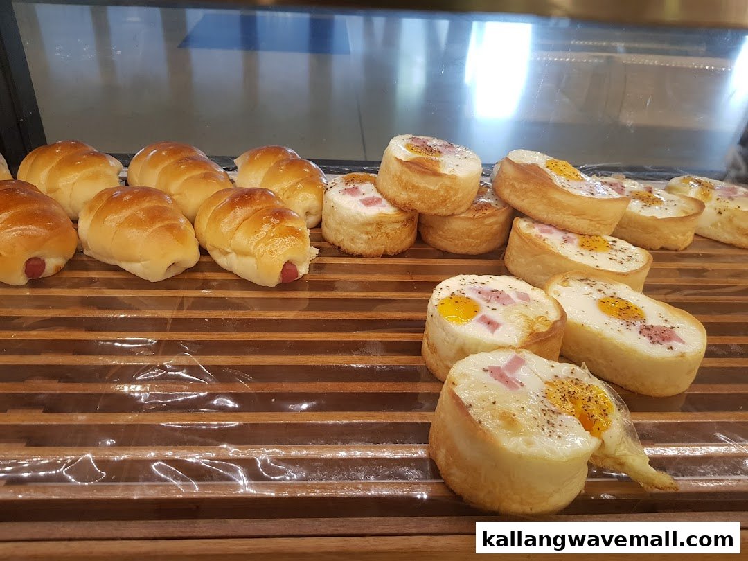 A display of freshly baked sausage rolls and savory egg and ham pastries in a bakery.