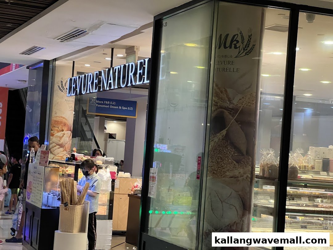 The illuminated storefront of MK Levure Naturelle, a bakery, showcasing its name and display cases.