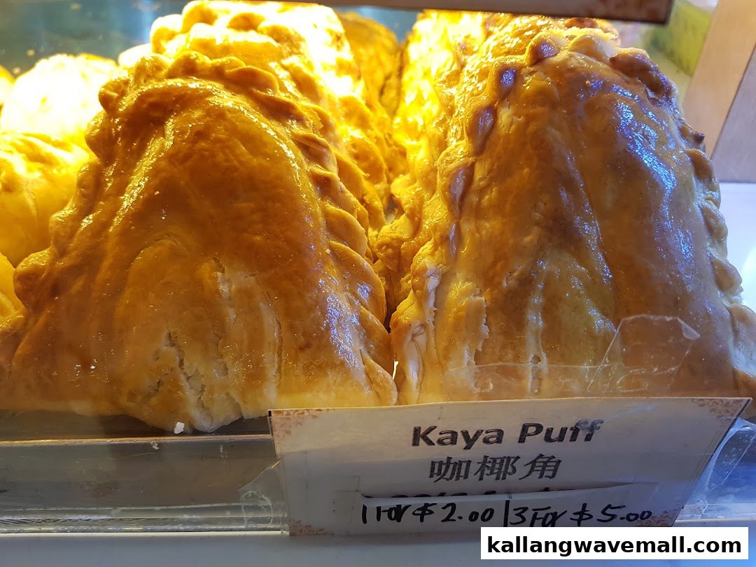 Close-up of golden-brown Kaya Puffs displayed in a bakery or pastry shop.