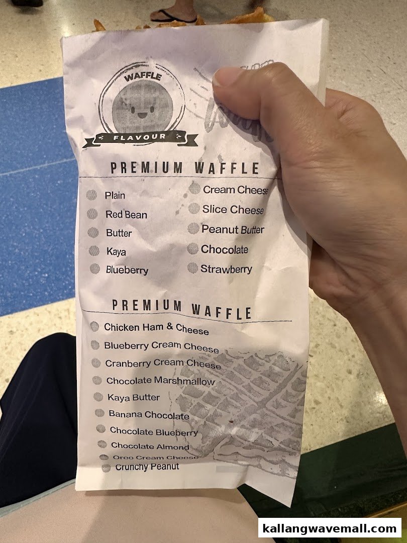 A hand holds a paper bag displaying a menu of various premium waffle flavors.