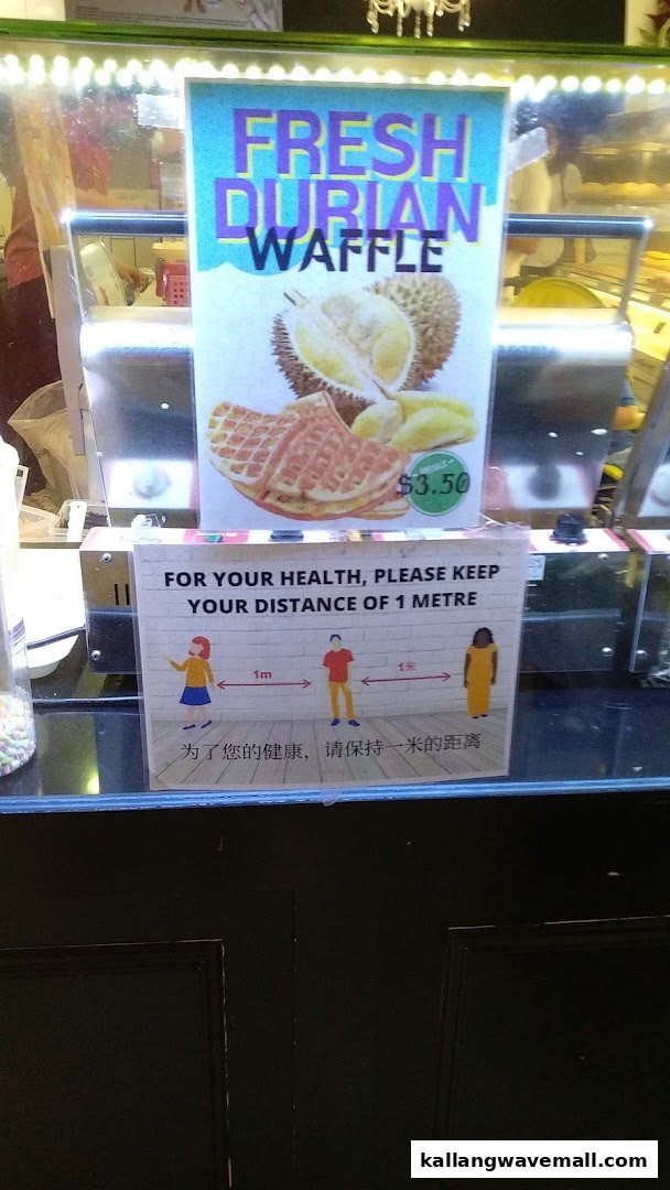A display sign advertising 'Fresh Durian Waffle' for $3.50, with a social distancing notice below it.