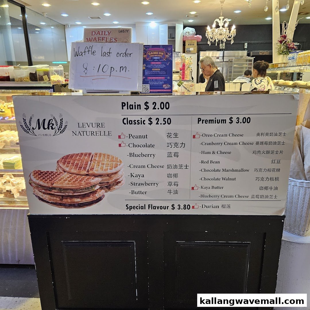 A menu board displaying waffle flavors and prices from MK Levure Naturelle, with a last order sign.