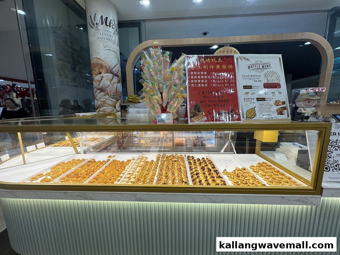 A vibrant display case showcasing various freshly baked pastries and tarts, with waffle and pastry menus visible.