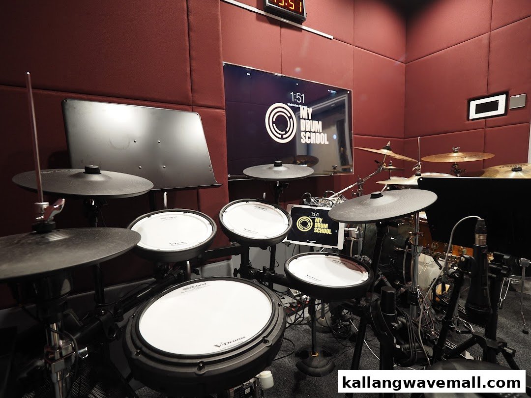 An interior shot of a drum practice room featuring electronic and acoustic drum kits.