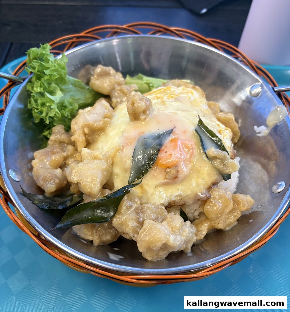 A close-up of a delicious-looking dish featuring crispy chicken, a fried egg, and rice in a metal bowl.