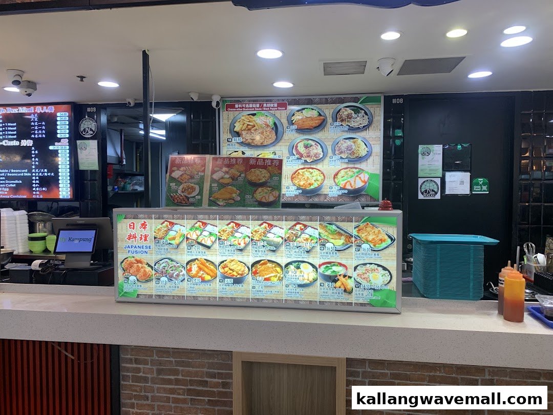 A vibrant food stall counter at My Kampung, showcasing various Japanese fusion dishes on illuminated menu boards.