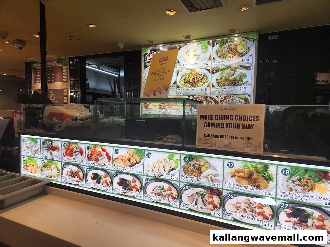 A brightly lit food stall counter displaying various traditional Asian dishes and drinks on digital menu boards.