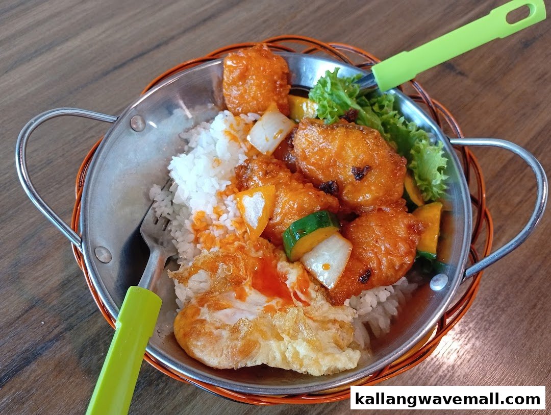 A delicious meal featuring rice, fried chicken, vegetables, and a fried egg served in a metal pan.